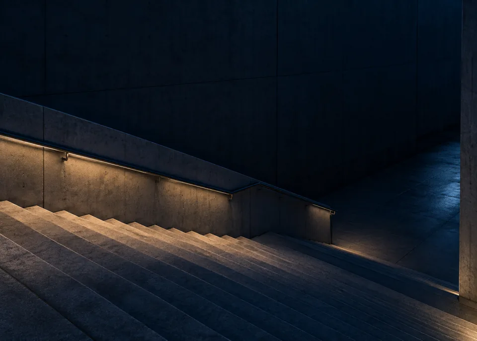 Blue Stair: A wide simple empty concrete stair descending diagonally across lower half into deep blue shade, soft architectural side light, dark quiet upper wall.