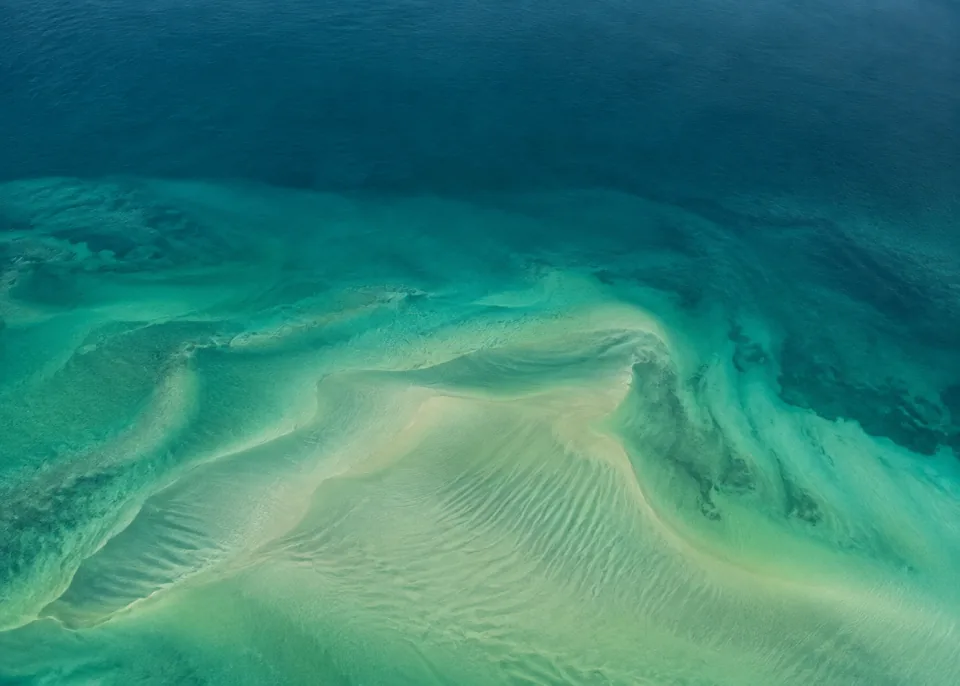 Emerald Shoal: Large organic pale sage sand shoal submerged beneath emerald water in lower middle, smoothly feathered depth transitions and calm dark teal upper field.