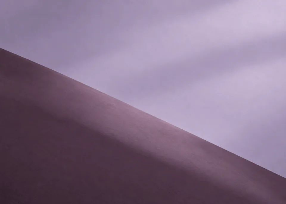 Lilac Diagonal: Broad lavender plane meets a dusty plum plane in a clean descending diagonal across lower two thirds, soft grazing light, no sharp white stripe.